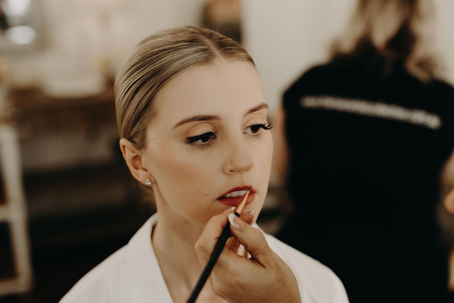 Close-up beauty preparation shot with makeup application in warm lighting.