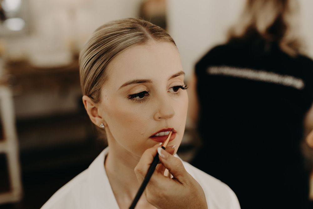 Close-up beauty preparation shot with makeup application in warm lighting.
