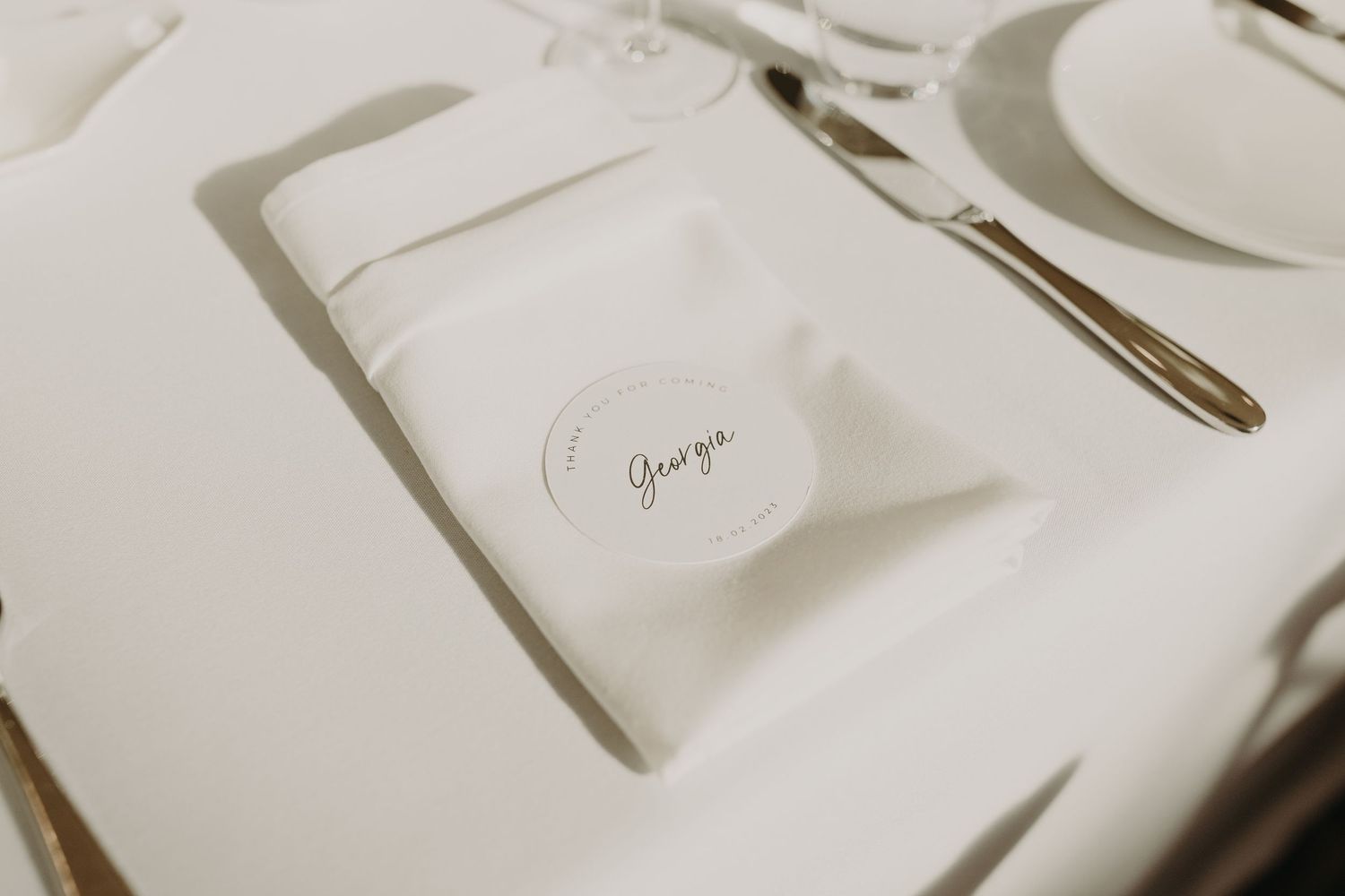 Close-up of elegant place setting with white napkin and silverware on formal dining table.