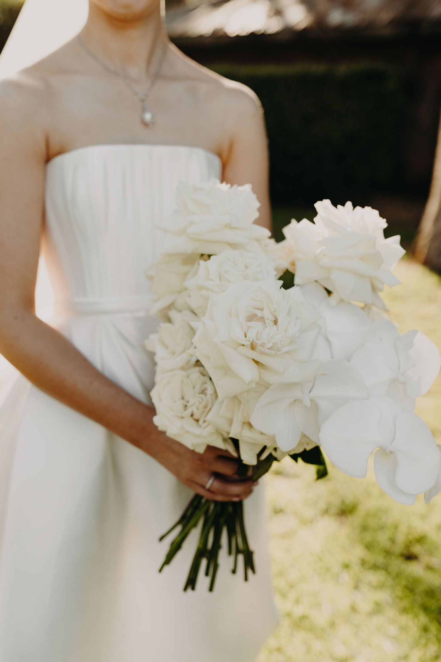 White peony bouquets held by bridesmaids in elegant wedding dresses.