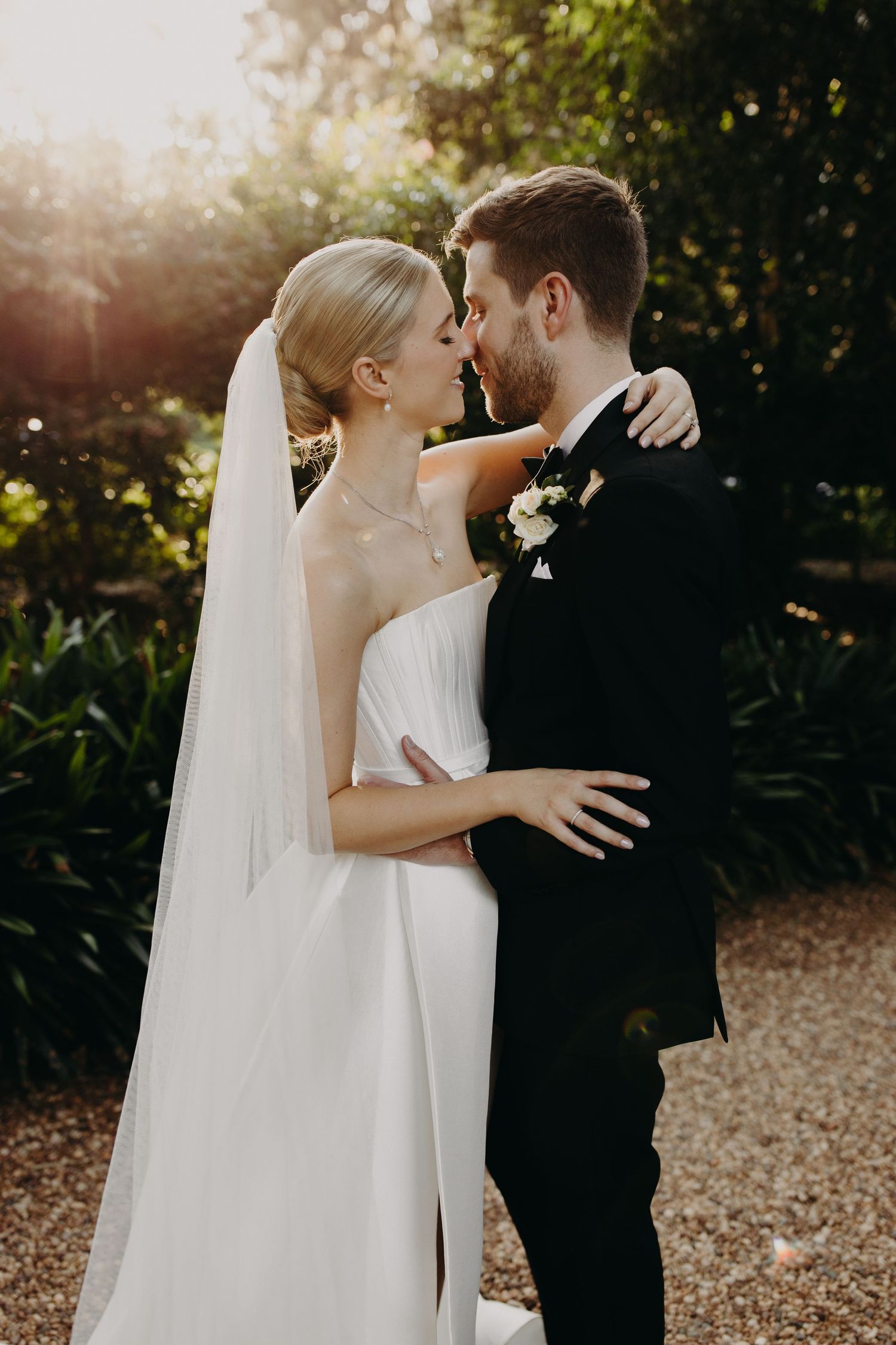 Romantic wedding couple shares an intimate moment in a garden setting during golden hour.