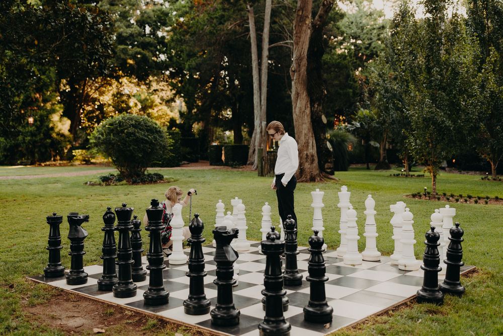 Large outdoor chess pieces create a unique backdrop for a wedding photo session.