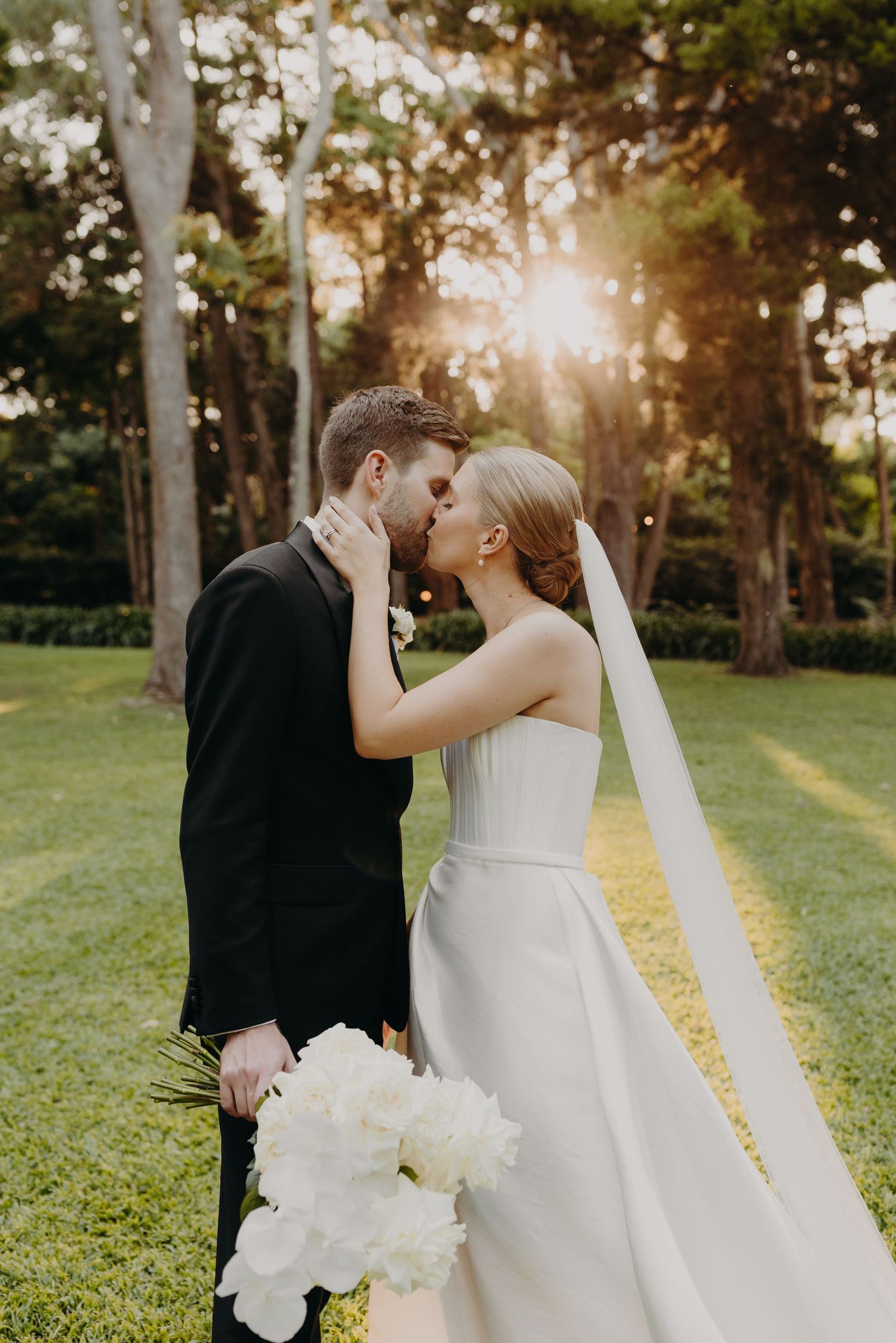 Romantic sunset wedding photos capture intimate moments between newlyweds in a garden.