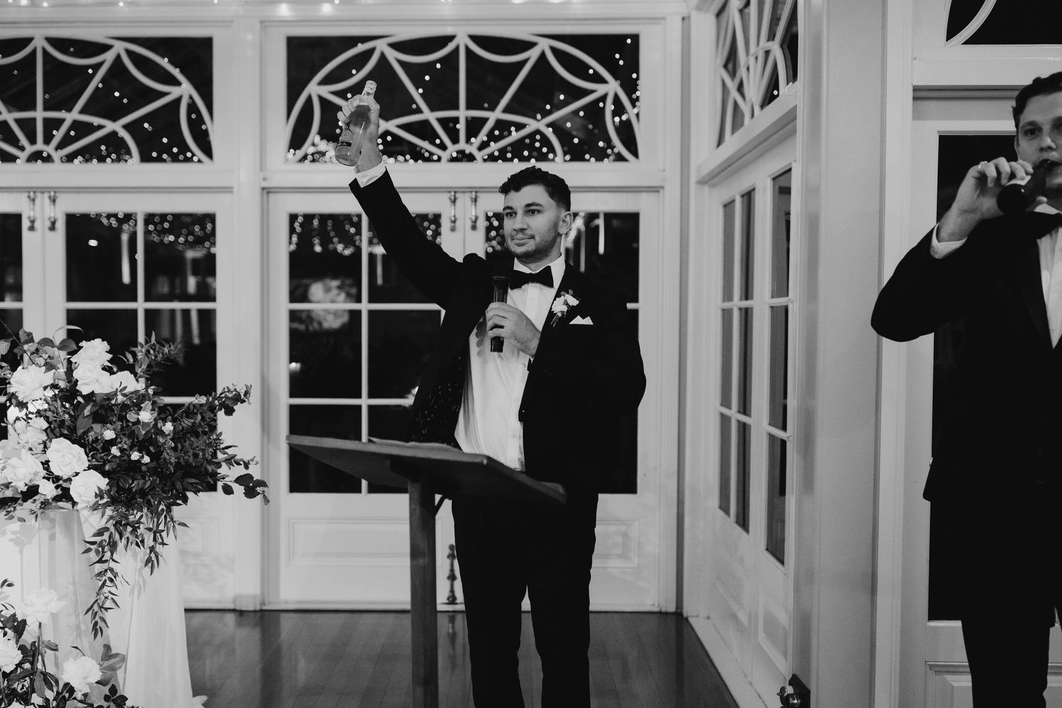 Person in formal attire gives a toast at an elegant wedding reception venue.