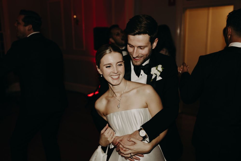 Wedding celebration with dancing couples in an indoor venue with warm lighting.