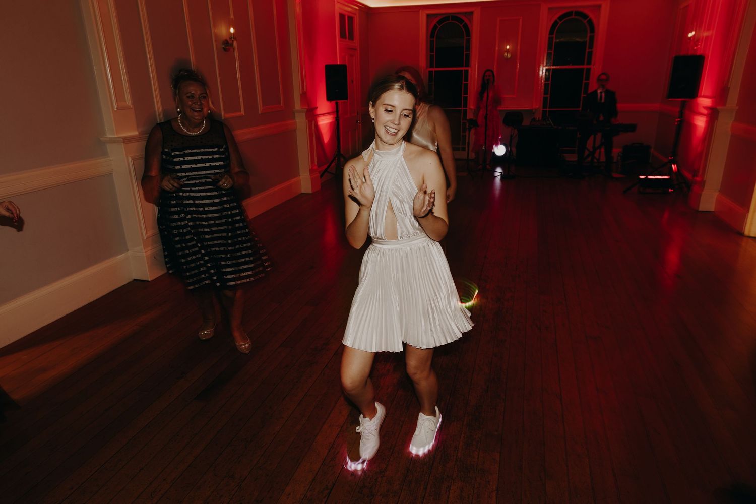 Dance floor scene with red ambient lighting in an indoor venue.