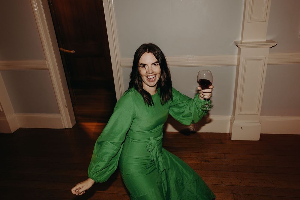 Person in bright green attire dancing on a wooden floor at an event.