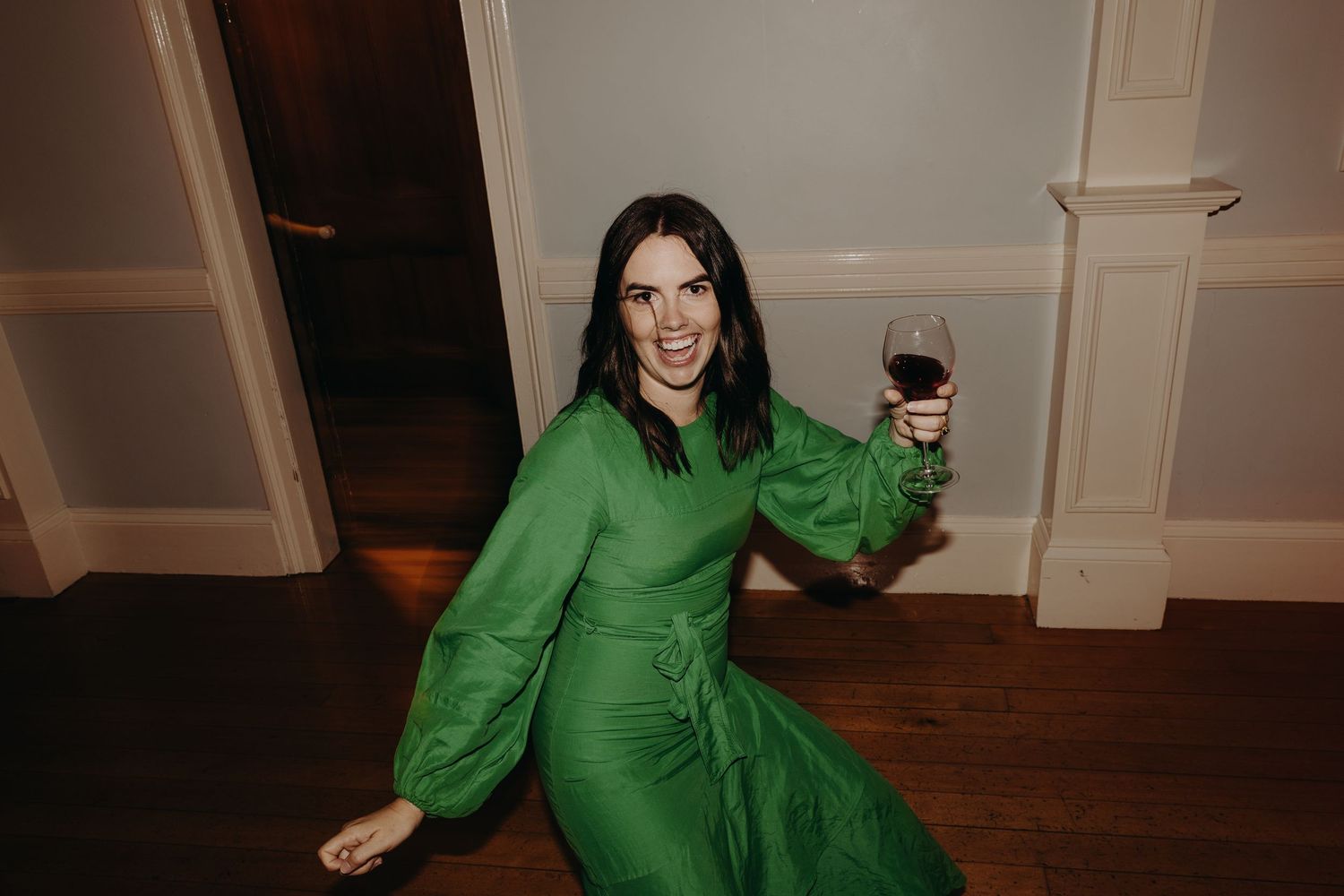 Person in bright green attire dancing on a wooden floor at an event.