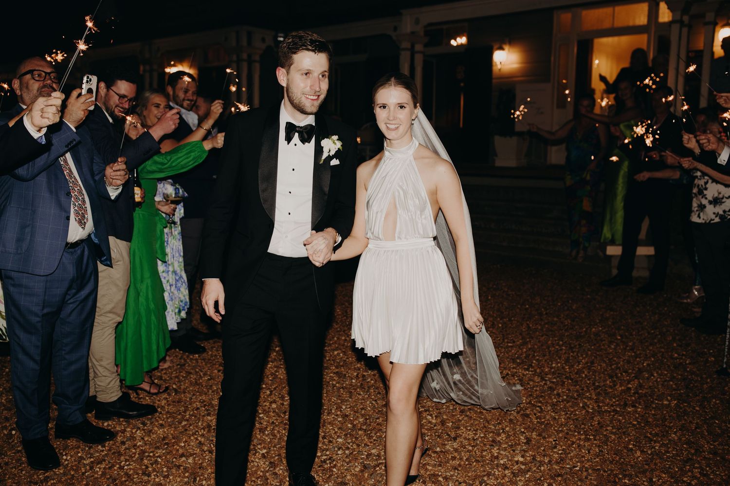 Wedding party exit at night with guests lining the walkway outdoors.
