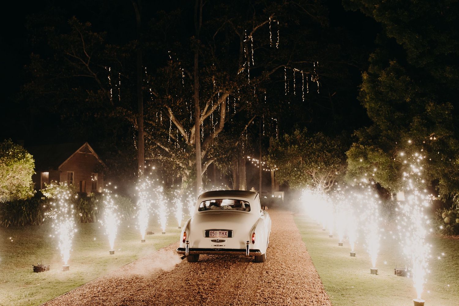 Sparklers line a dark pathway creating a magical exit tunnel effect at night.