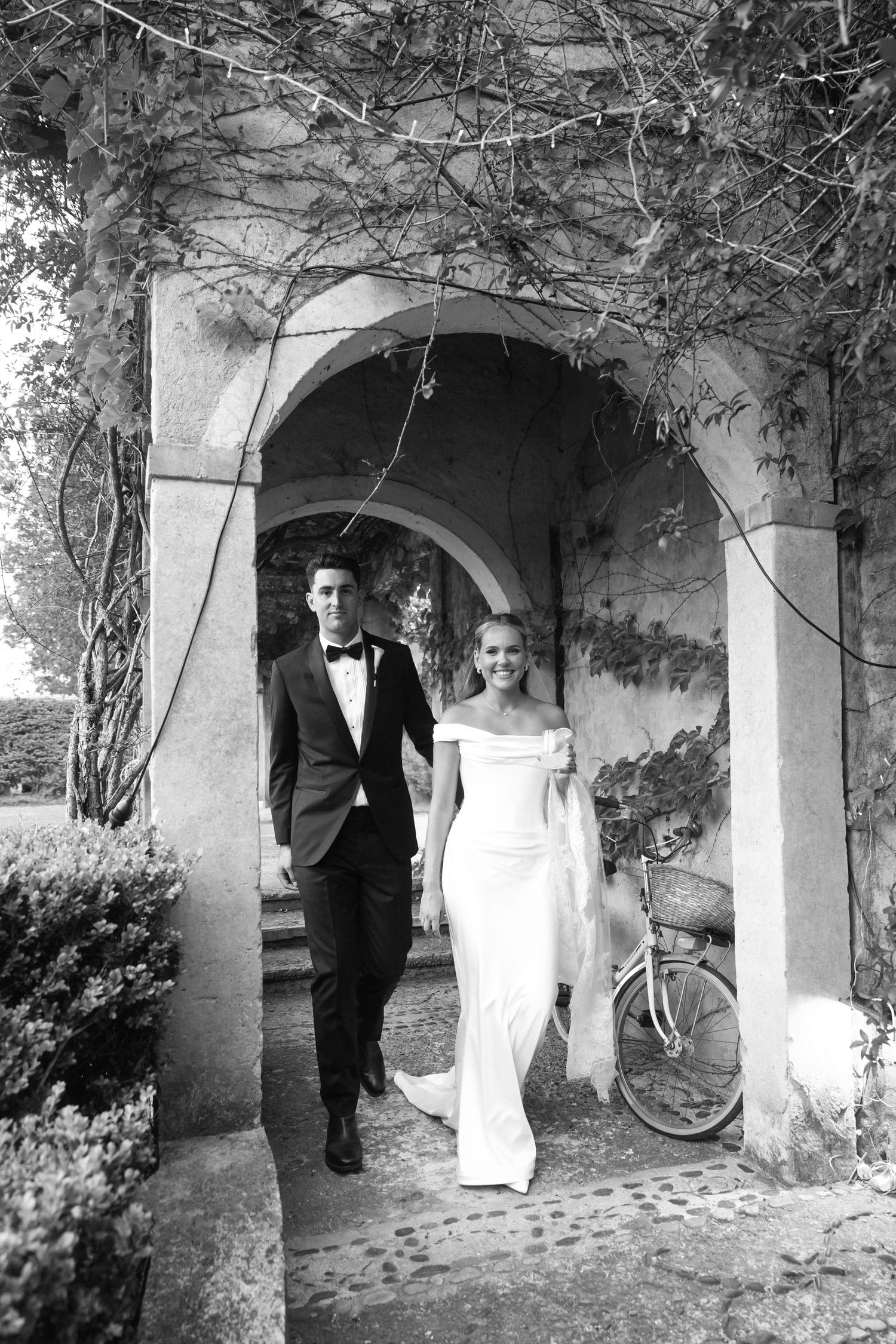 Black and white candid photo of a couple walking as the bride's dress flows in the breeze.