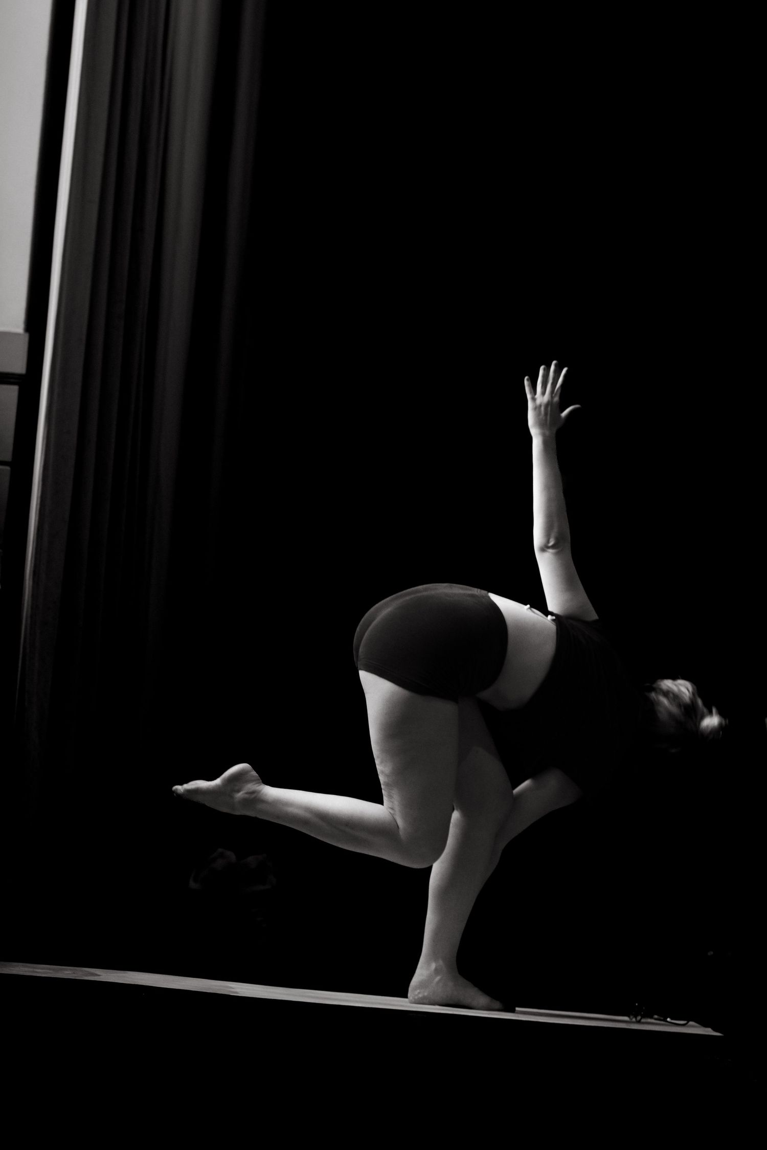 a woman practising yoga alone on a black background while being captured by Stockholm yoga retreat photographer