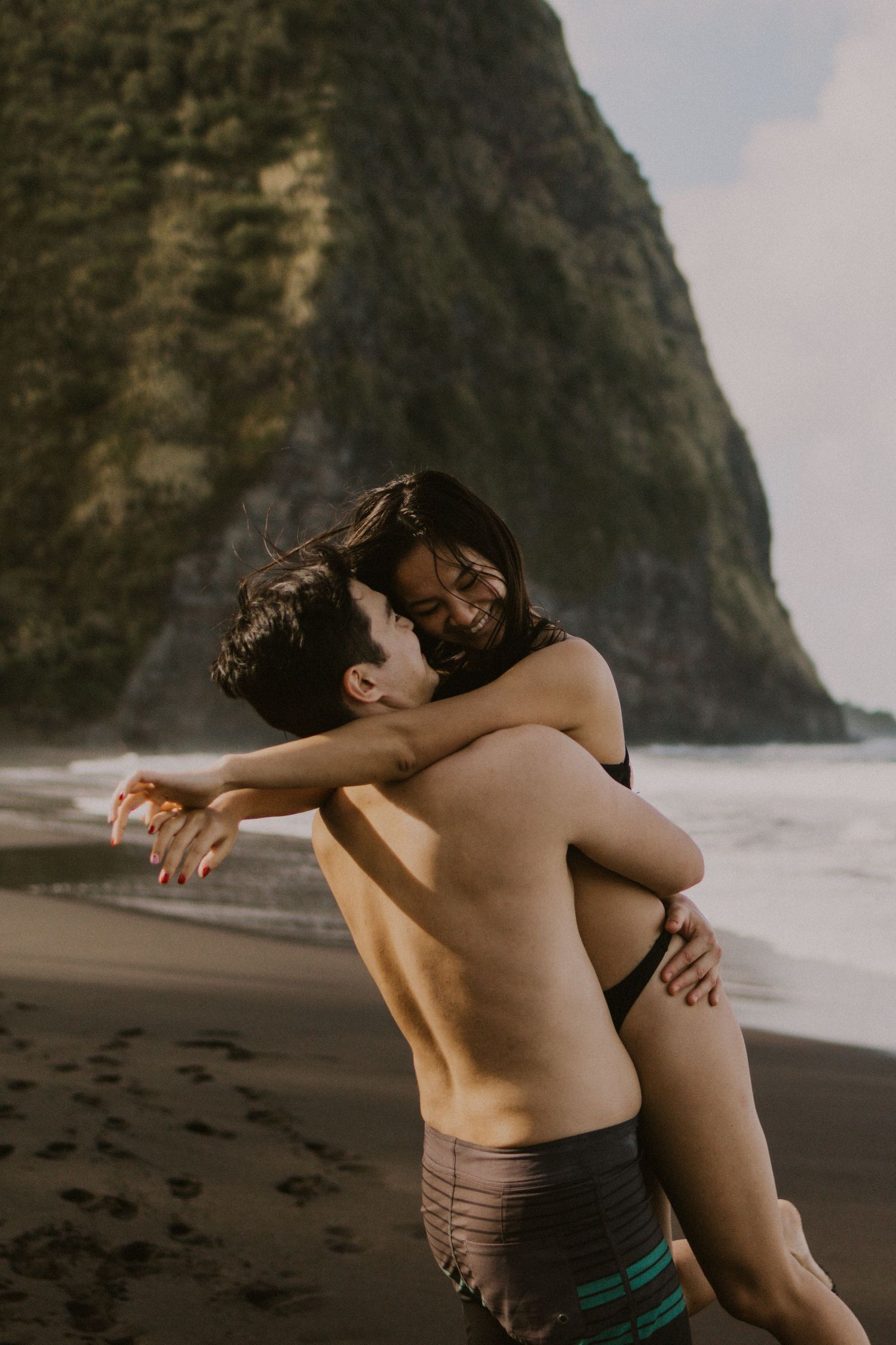 couple hugging on a beach in Hawaii, elopement activities, cute destination wedding pictures