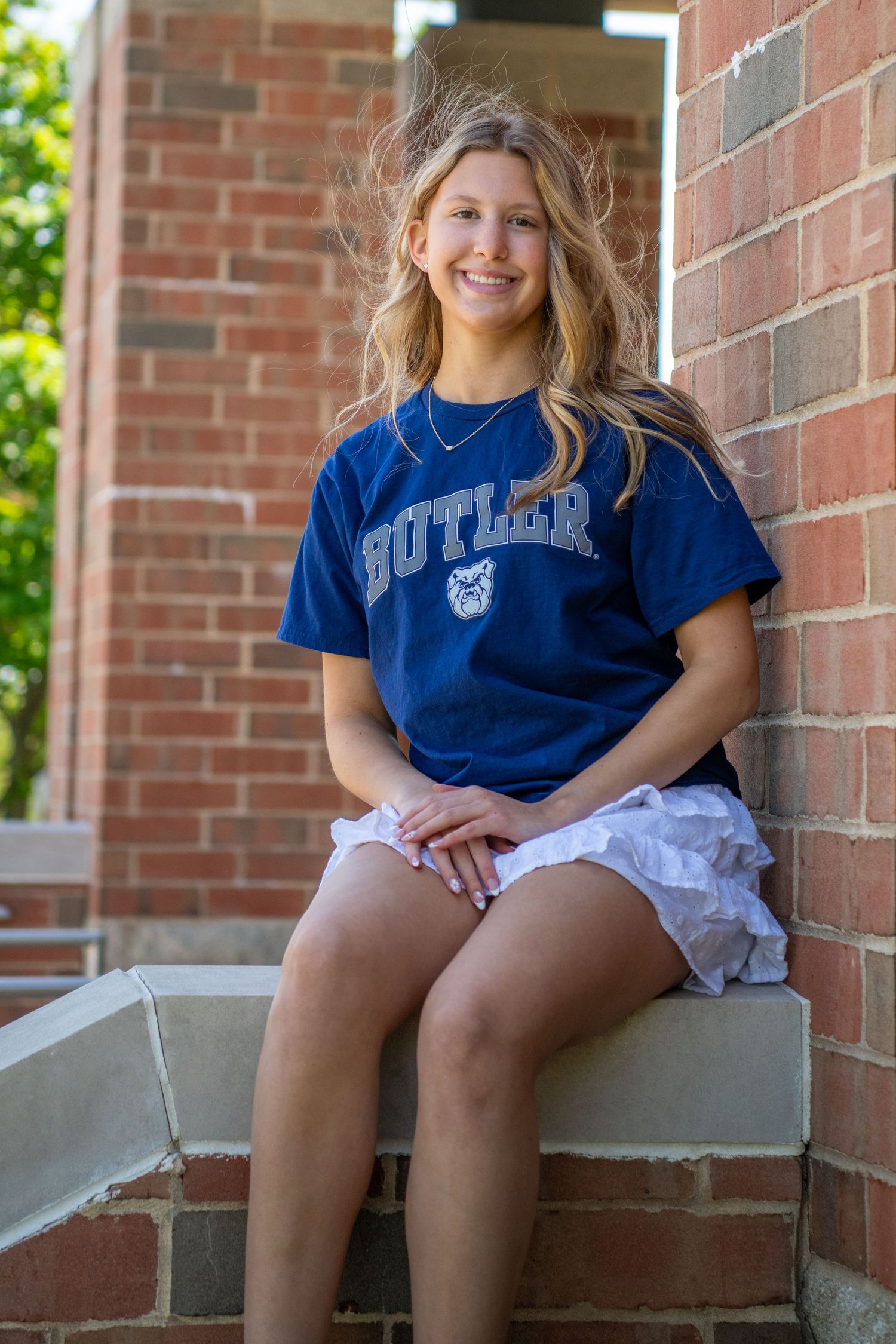 Four similar photos show someone in a blue Butler shirt sitting on concrete steps against a brick wall.