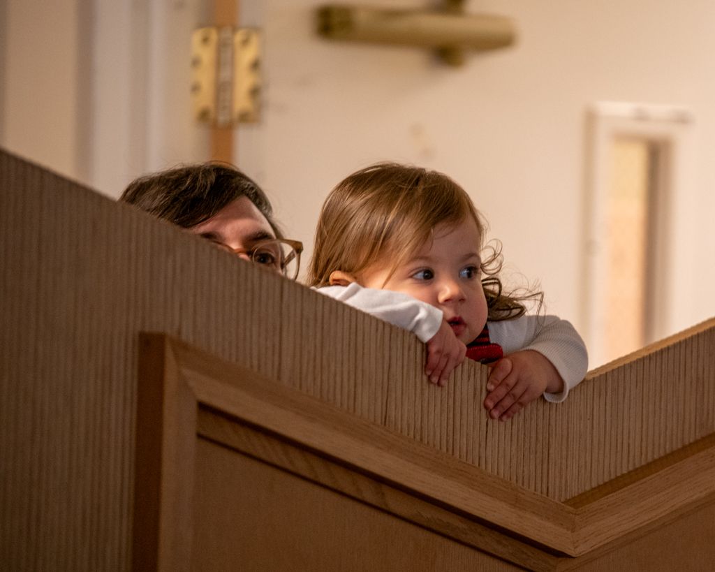Playful candid shots peeking over wooden furniture in an indoor setting.
