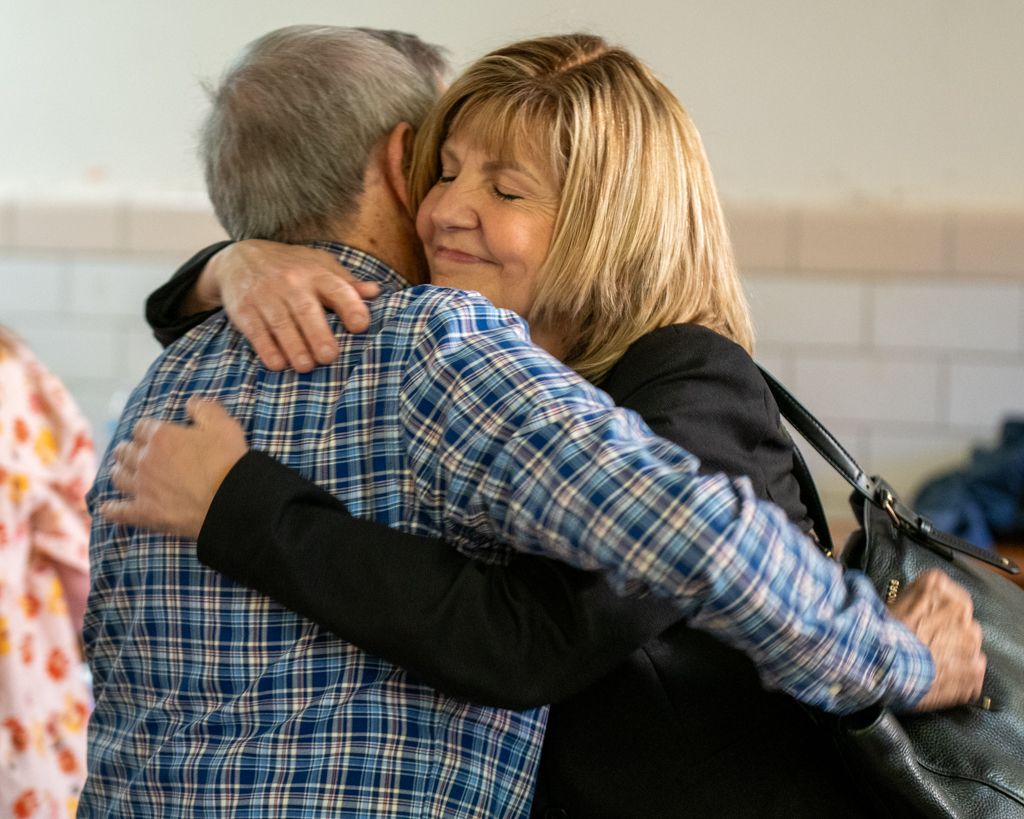 Warm embraces shared between people in an indoor setting with natural lighting.