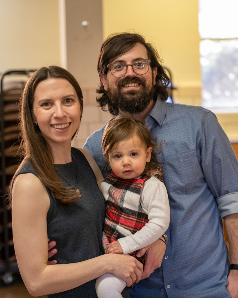Family members smile warmly while posing together indoors.