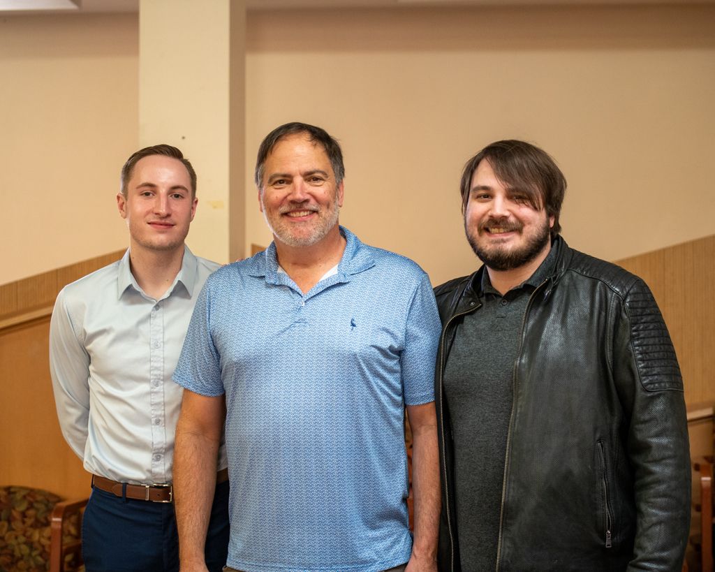 A group of colleagues standing together in a professional office setting wearing business casual attire.