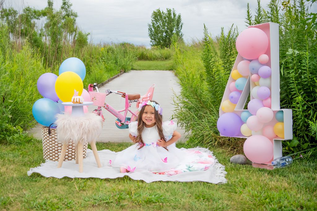 Birthday party setup outdoors with balloon number 4, blankets and decorations.