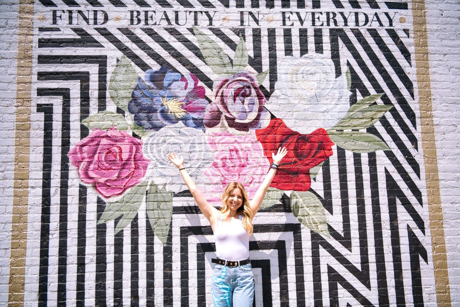 Colorful paper roses and geometric patterns decorate a wall display with text 'Find Beauty in Everyday'.