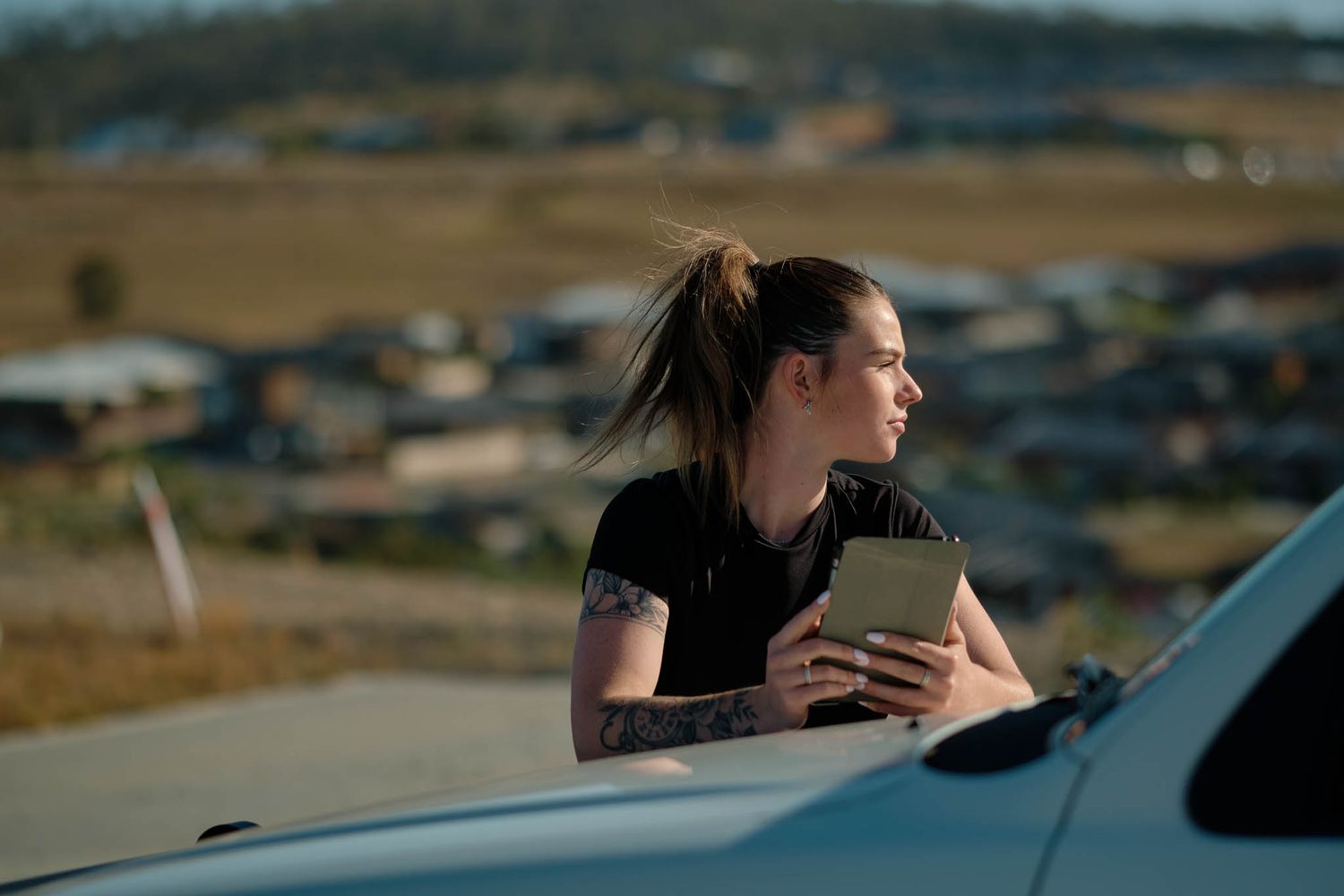 Young female tradie holding an ipad in late afternoon light