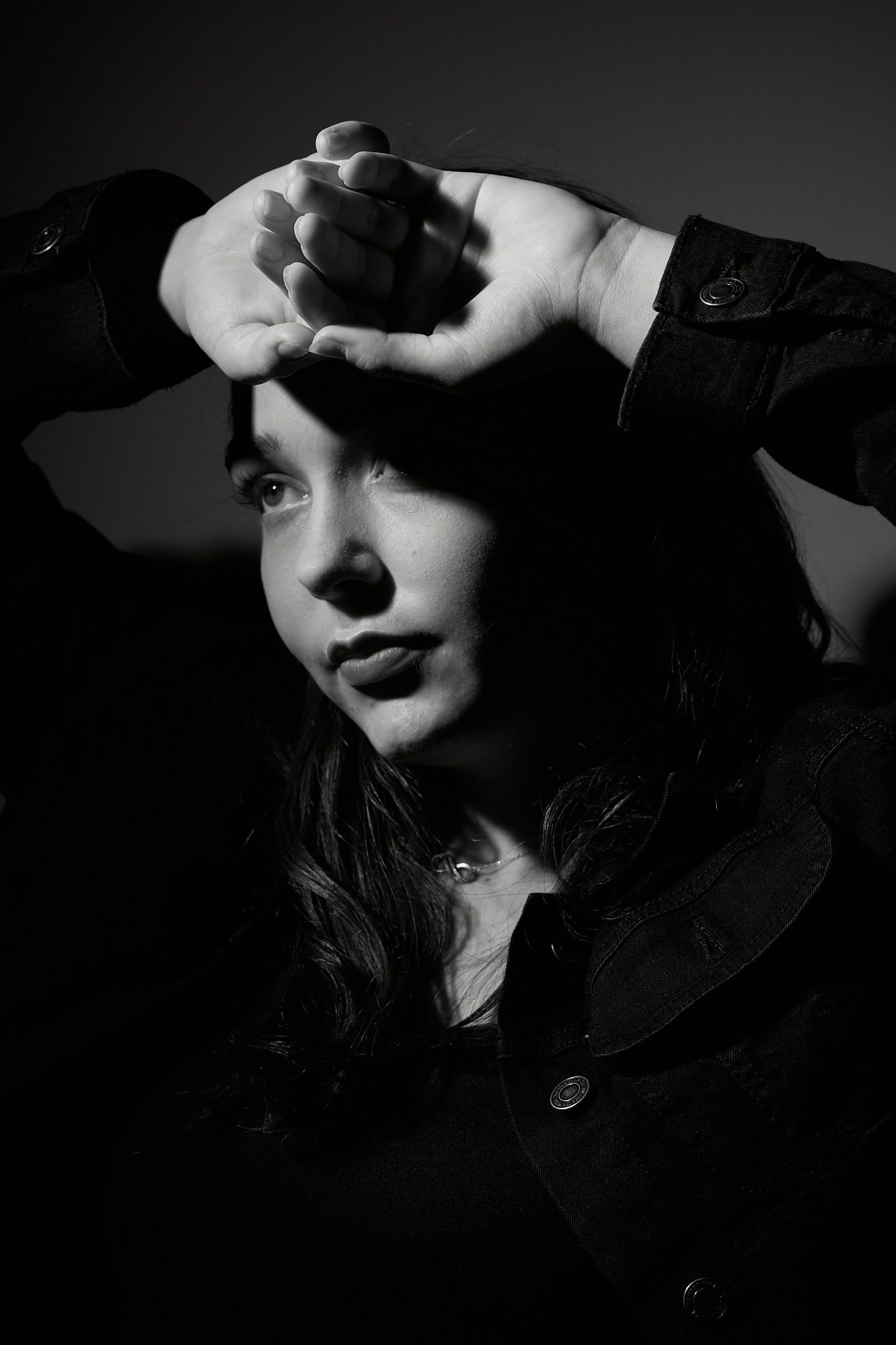 Black and white photo of young female model lit by a single light in studio