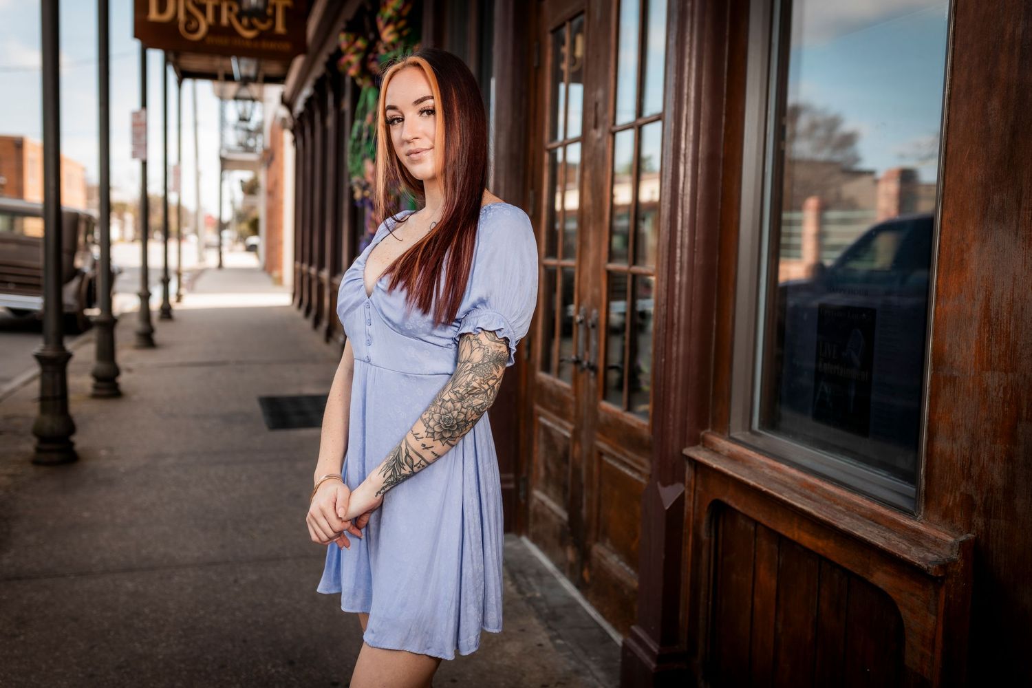 Street style portrait in light blue dress against rustic storefront.