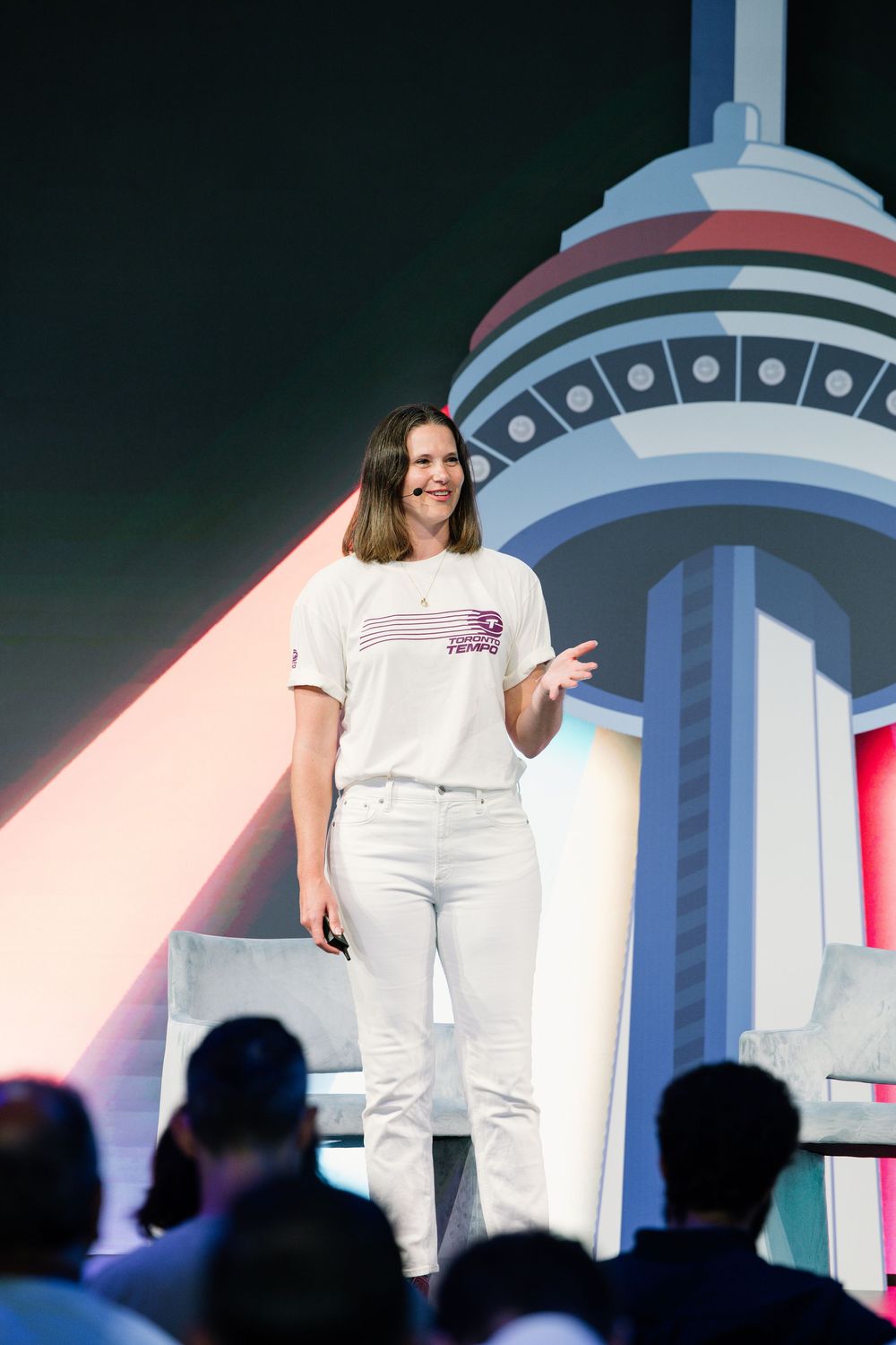A presenter speaking on stage setup with futuristic circular design elements and lighting.