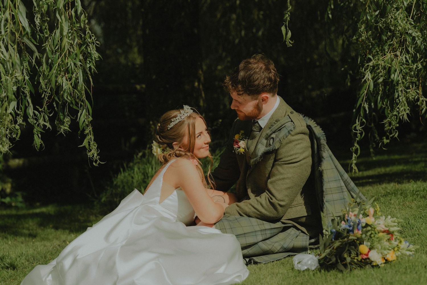 Romantic wedding couple embracing in front of blooming white flowers.
