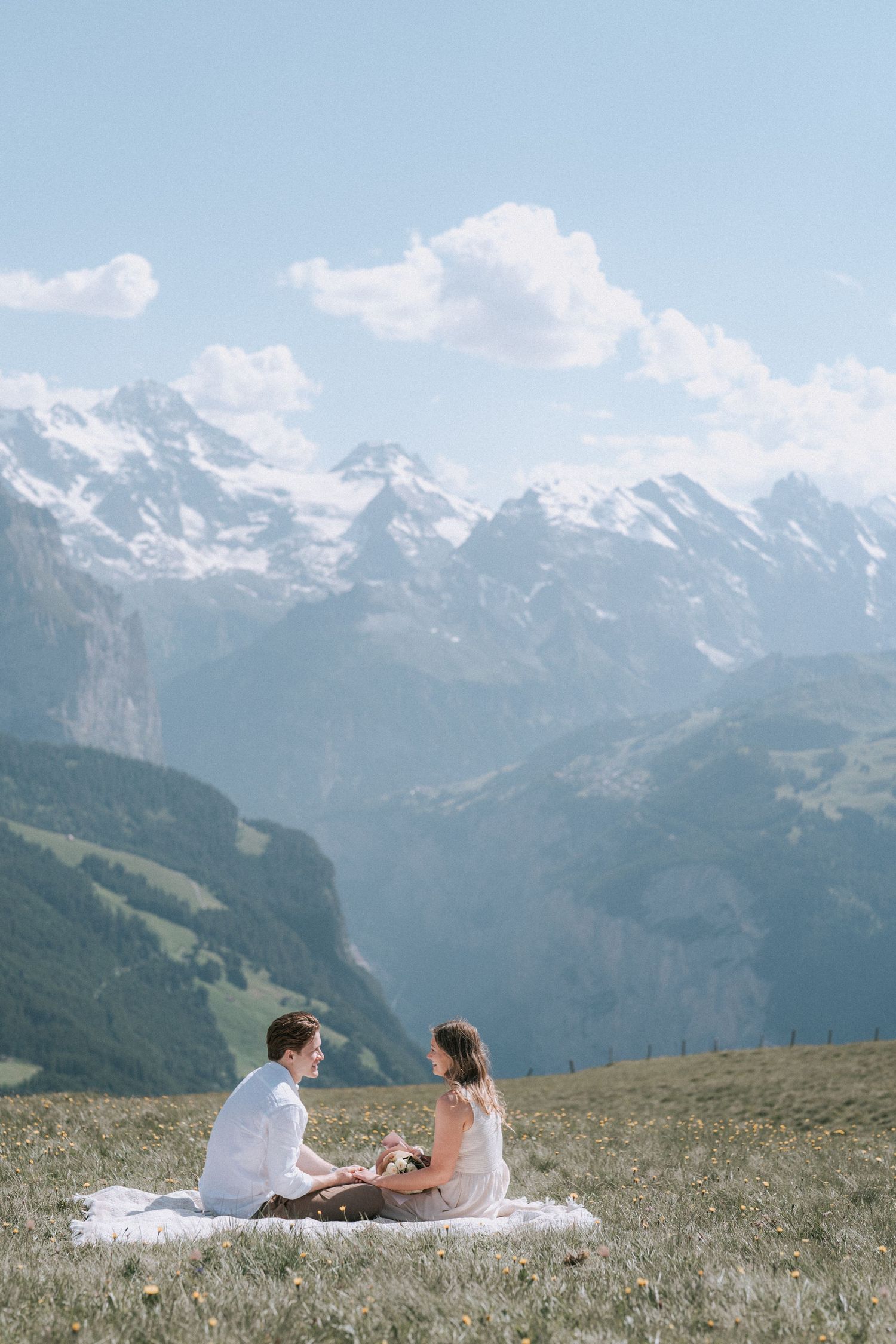 Couple enjoying a picnic on a mountain meadow with Alpine peaks in the background.