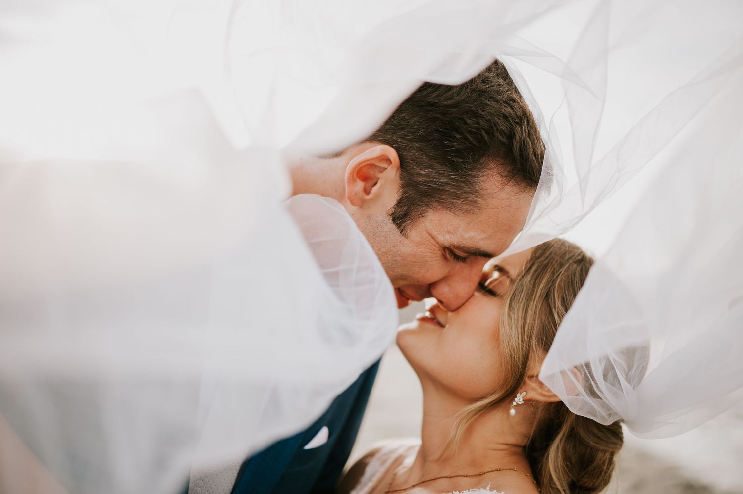 Photography wedding couple romantically kissing under veil for golden hour wedding portraits at Williams Beach Comox Valley Vancouver Island