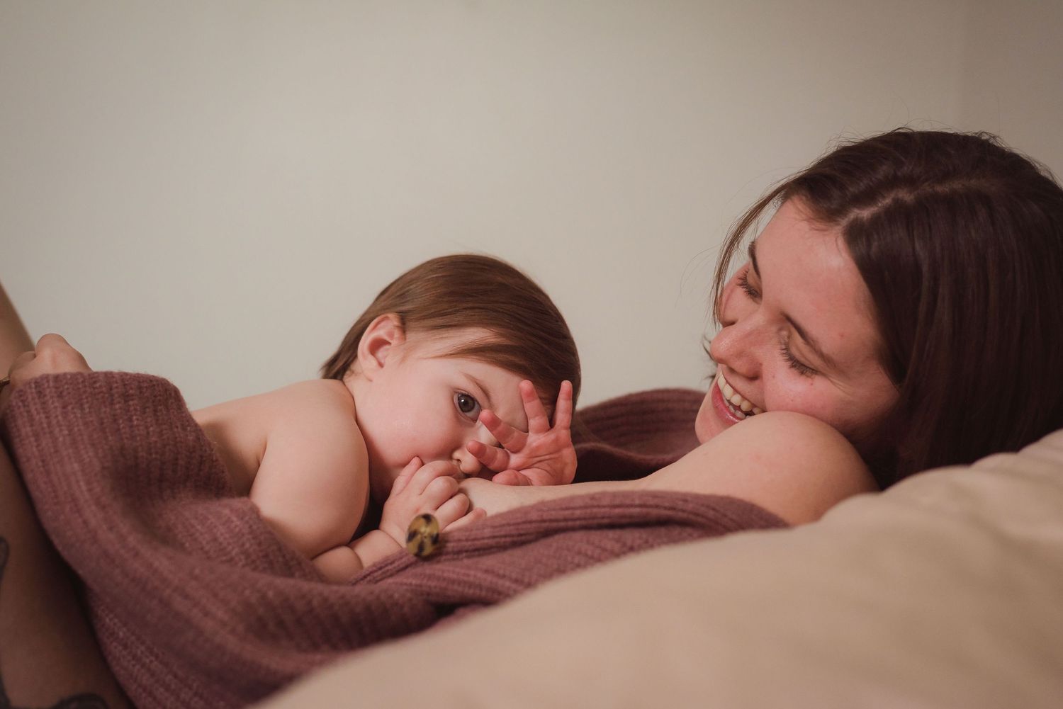 A tender moment between parent and child cuddling under a cozy brown blanket.