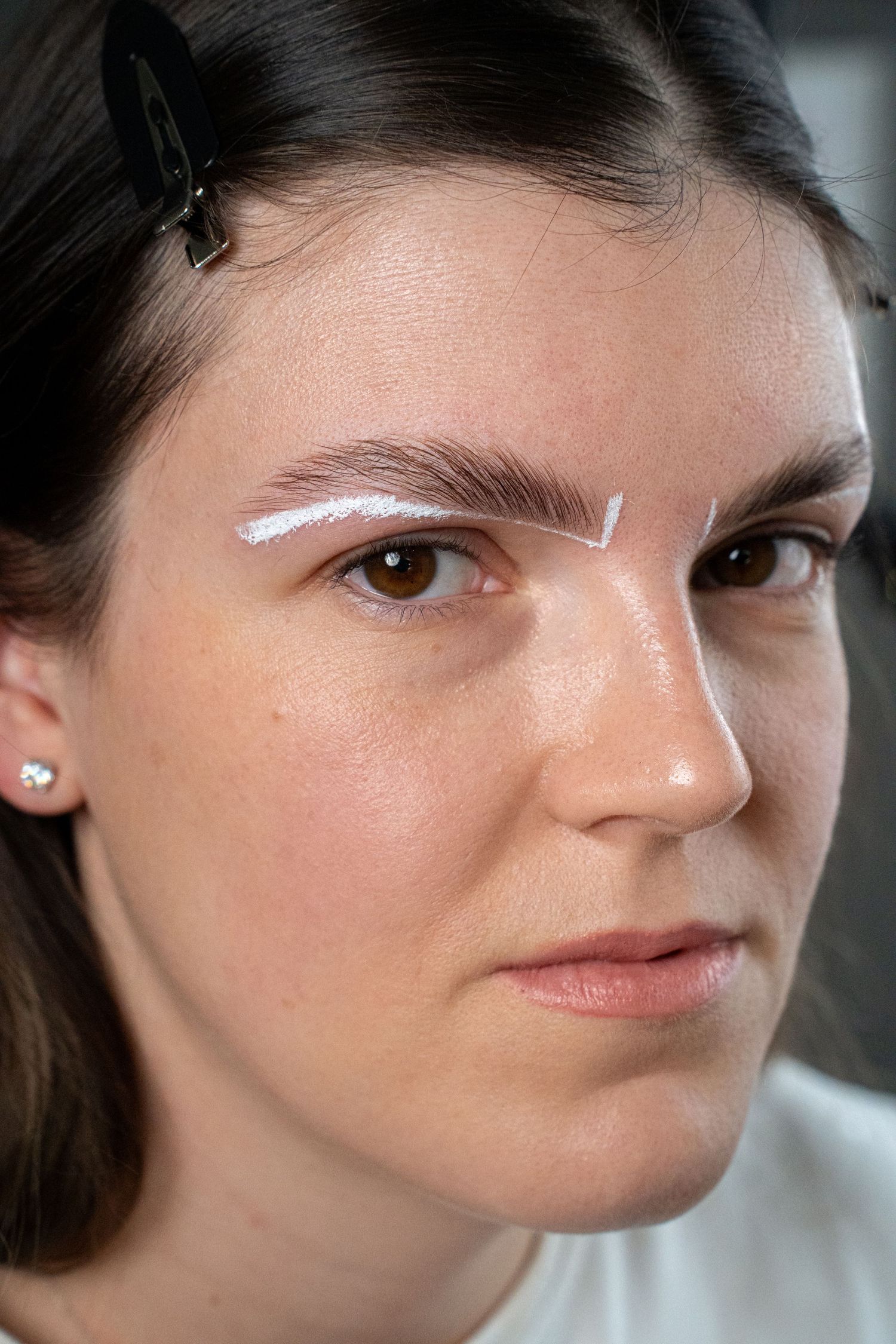 White product applied in a curved line over the eyebrow area showing a beauty treatment technique.