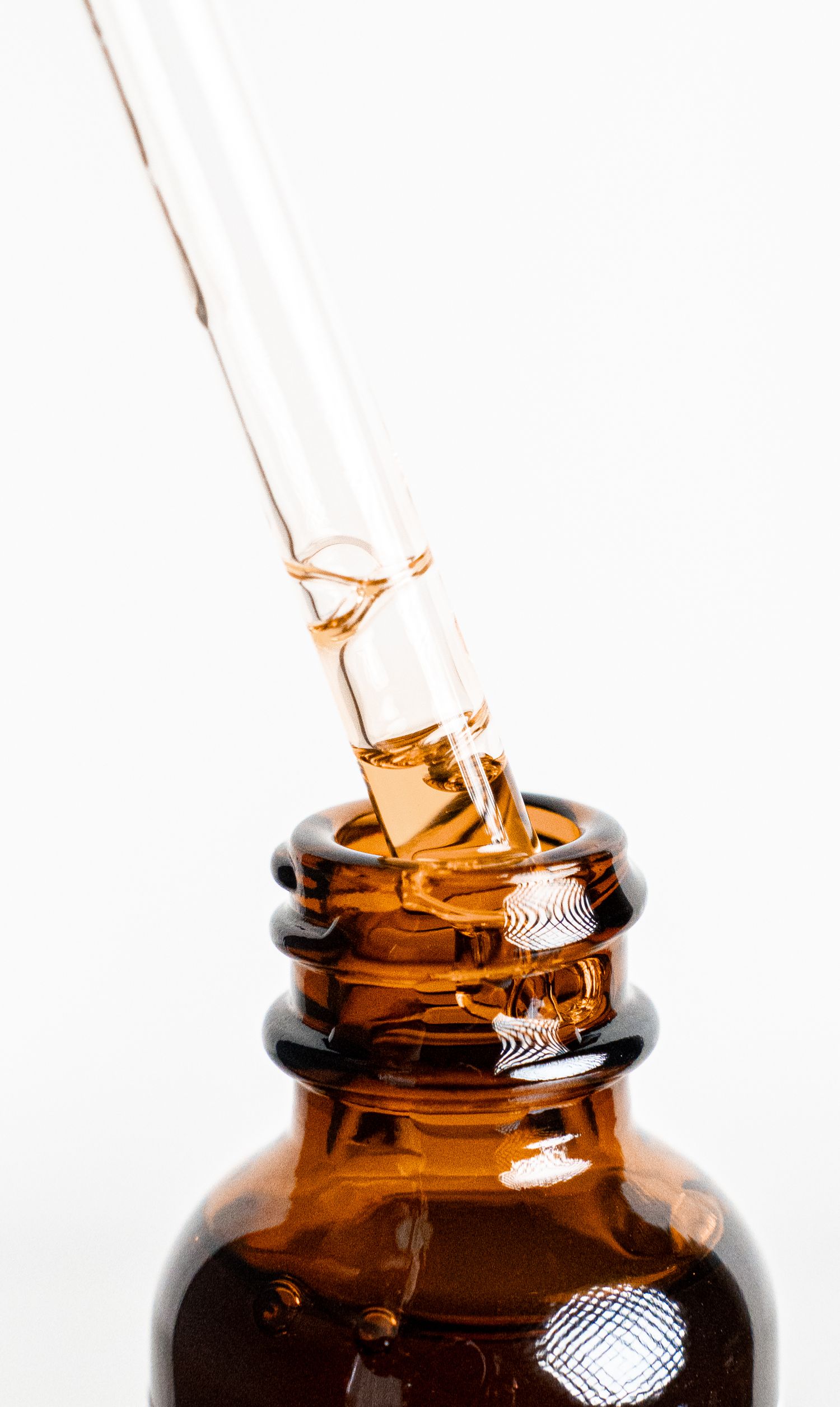 Closeup of amber glass dropper bottle with liquid being dispensed.