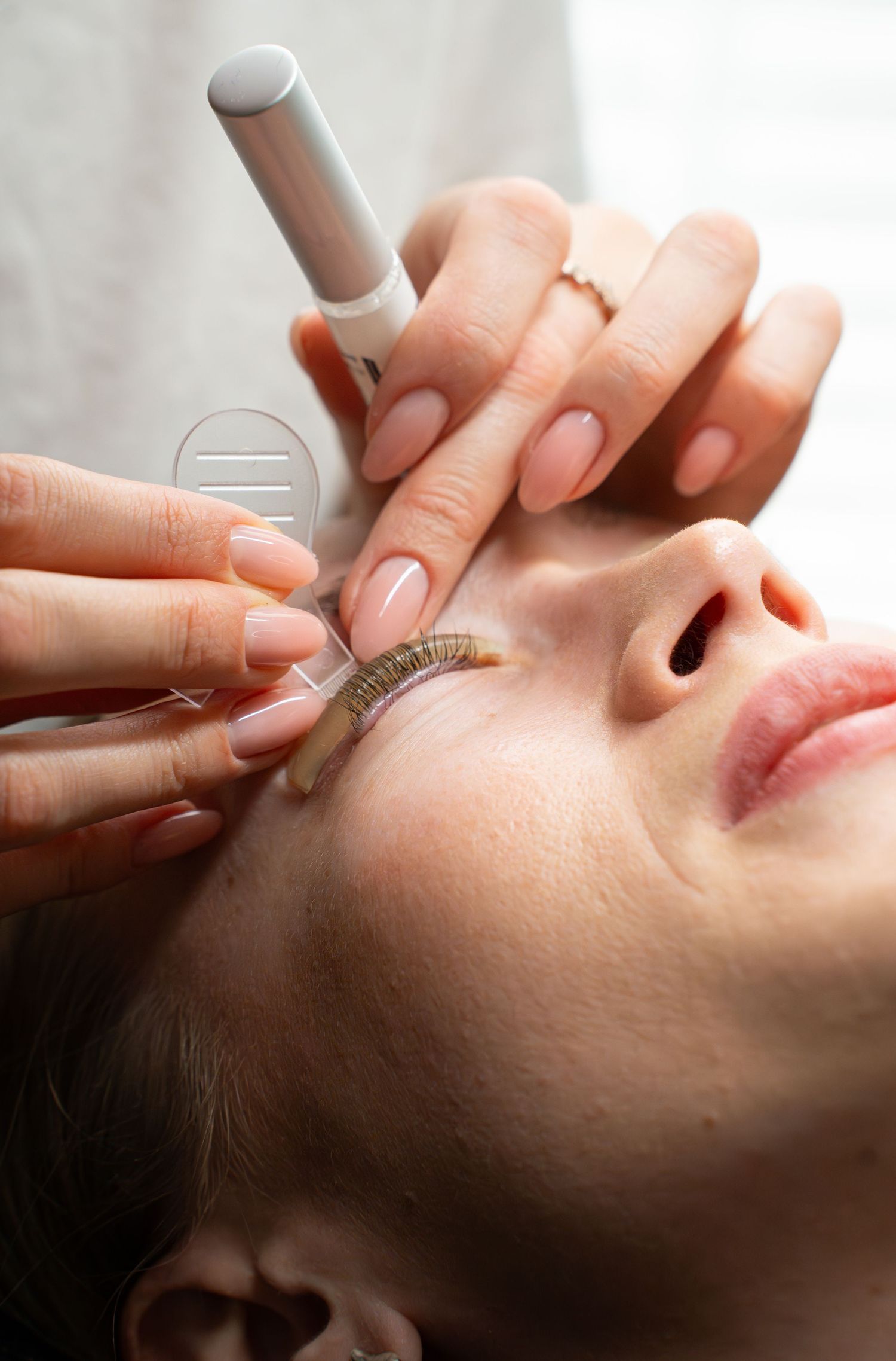 Close-up of an eyelash extension application procedure showing precise placement of individual lashes.