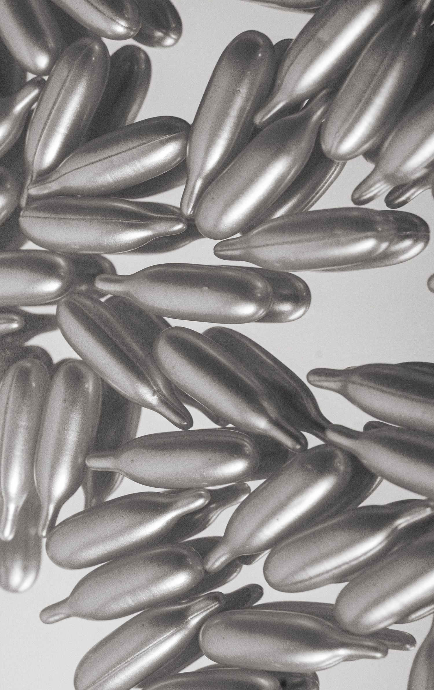 Close-up view of silver metallic capsules or pills arranged in a pattern against a light background.