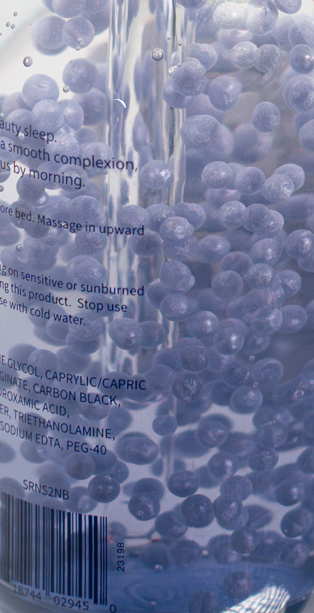 Close-up of blue beauty product ingredients with visible text and bubbles in liquid.