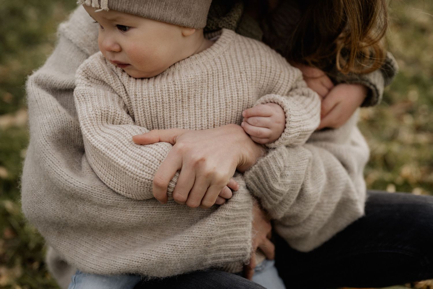 A tender hug moment captured between mother and son wearing cozy beige sweaters on an autumn day.