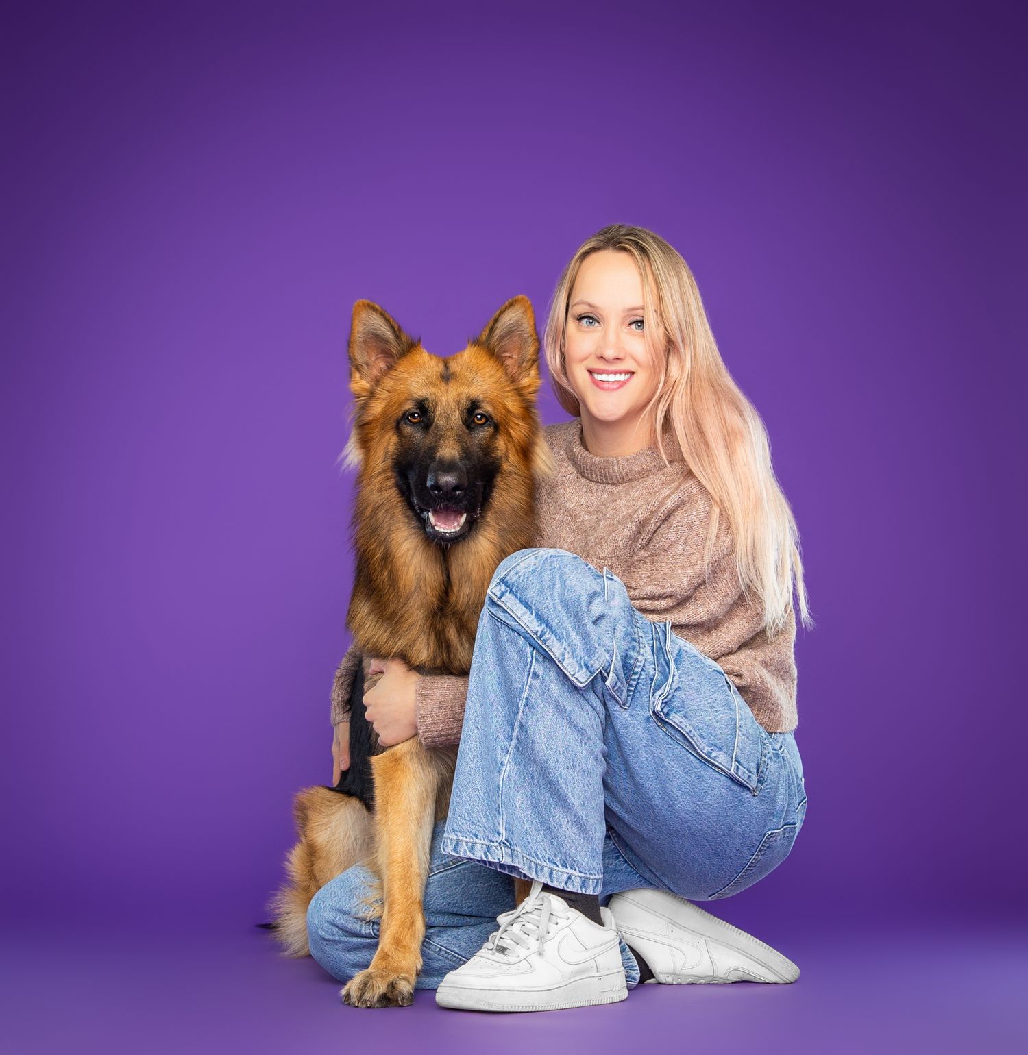 German Shepherd dog lounging with companion on purple background.