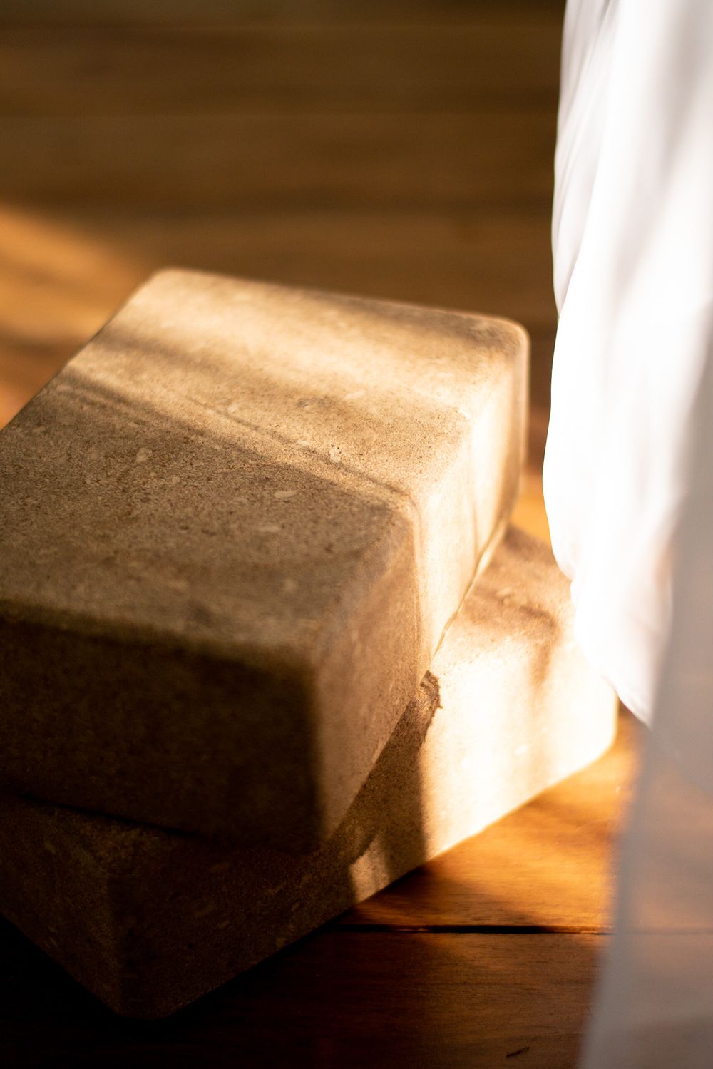 Two blocks sitting on a wooden surface in dramatic lighting.