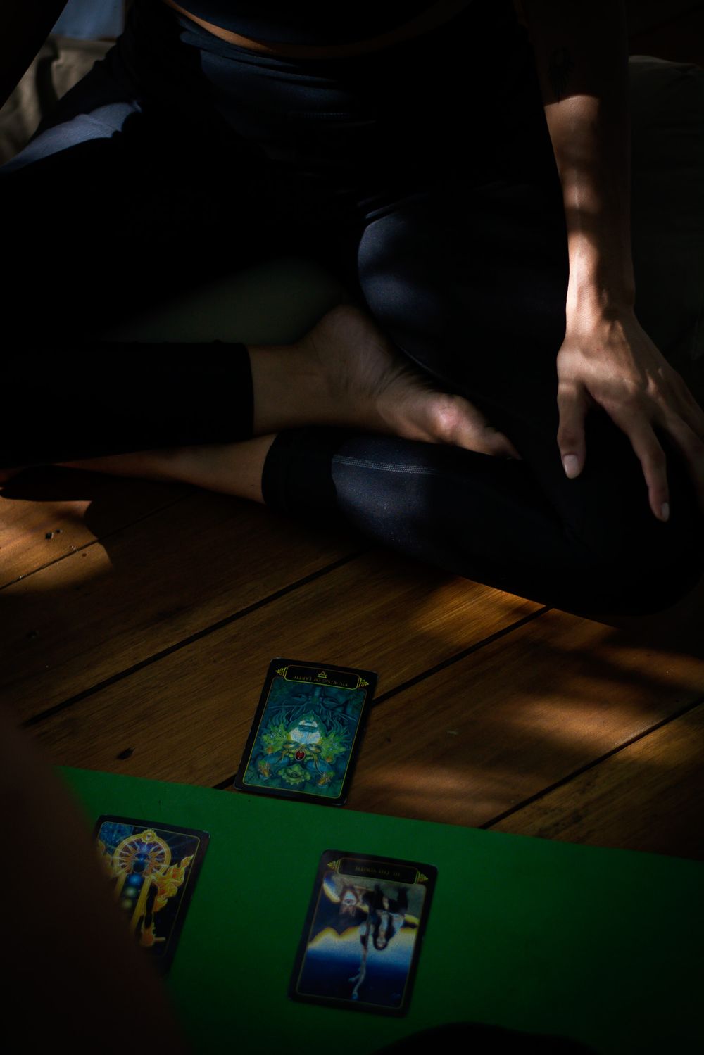 Tarot cards laid out on green surface with person sitting in meditation pose.