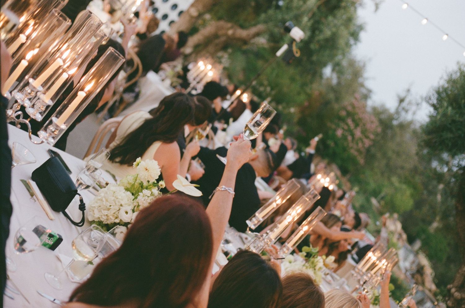 Two hands toast with wine glasses in an intimate black and white moment.