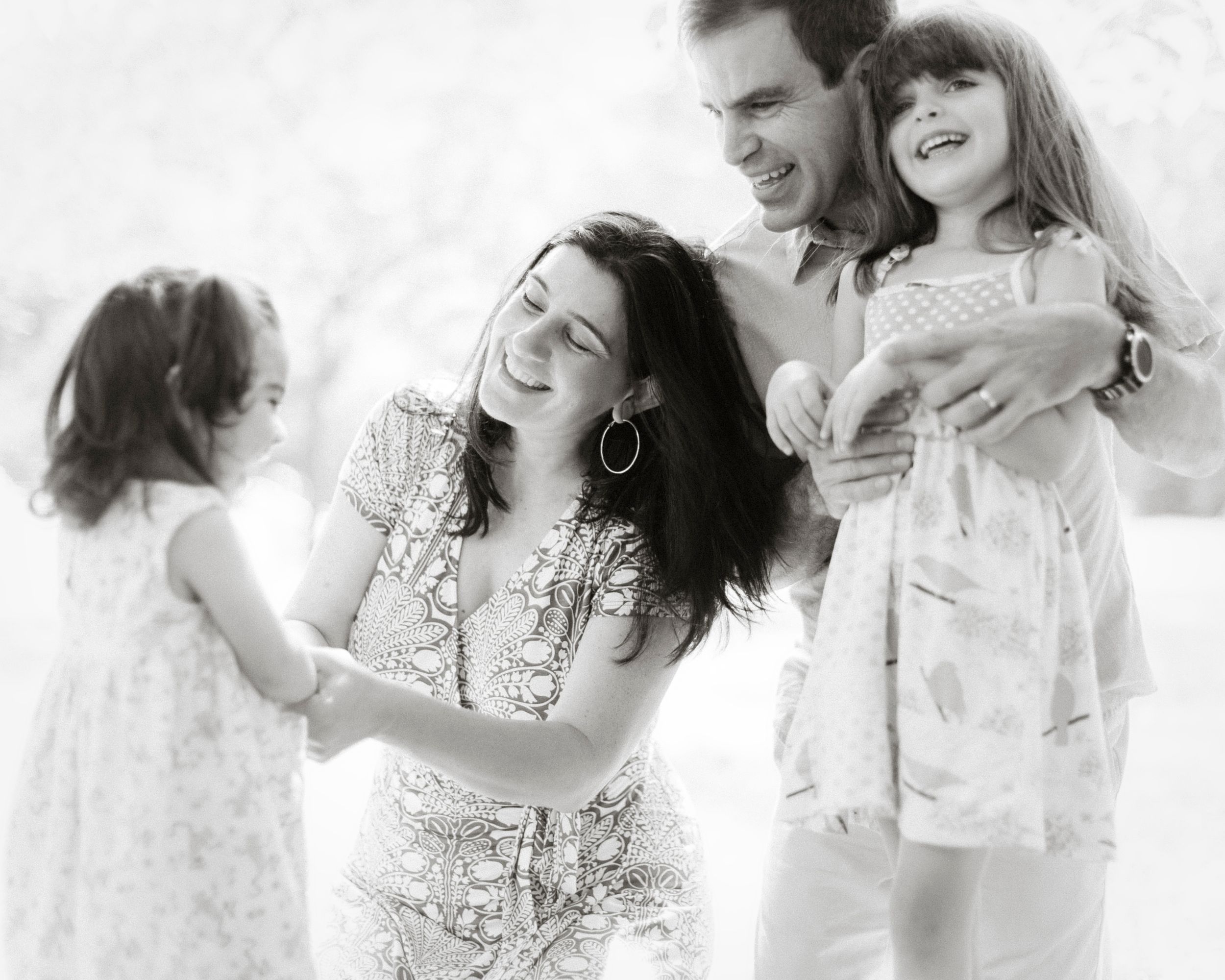 A black and white family portrait showing natural laughter and movement during a photoshoot.