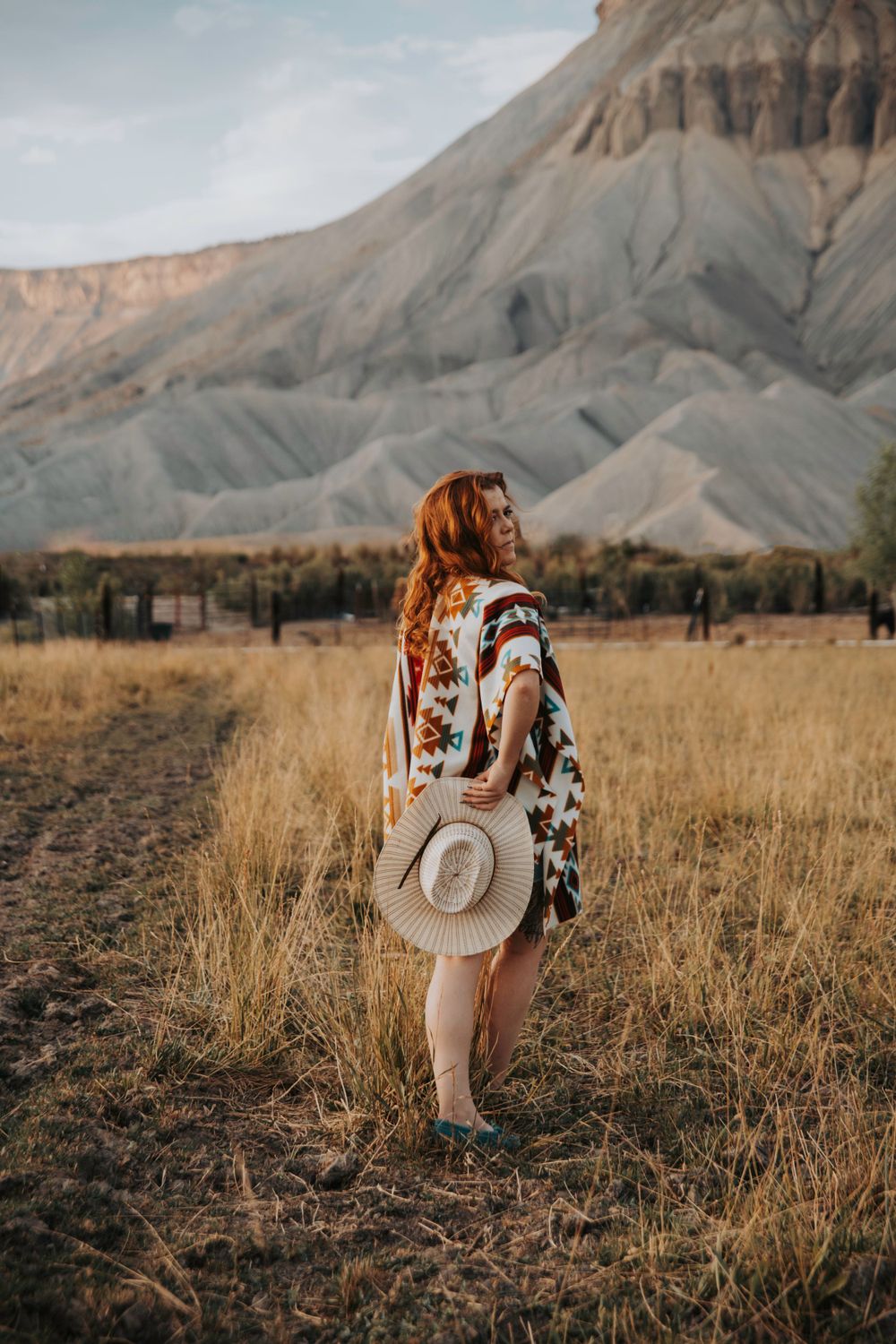Rustic western scene with cowboy hat silhouetted against dramatic desert cliffs.
