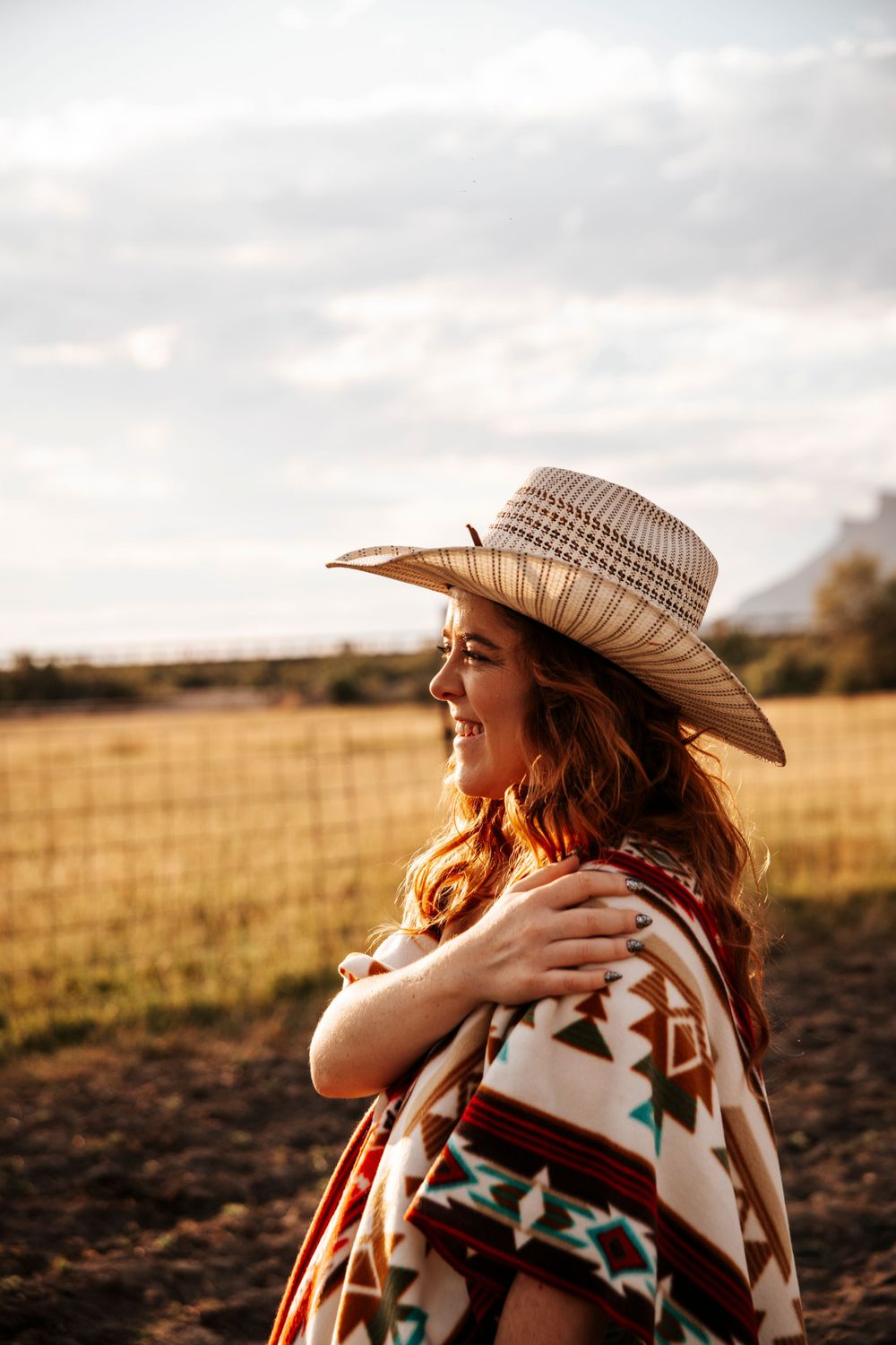 Profile portrait in cowboy hat and tribal print blanket at golden hour.