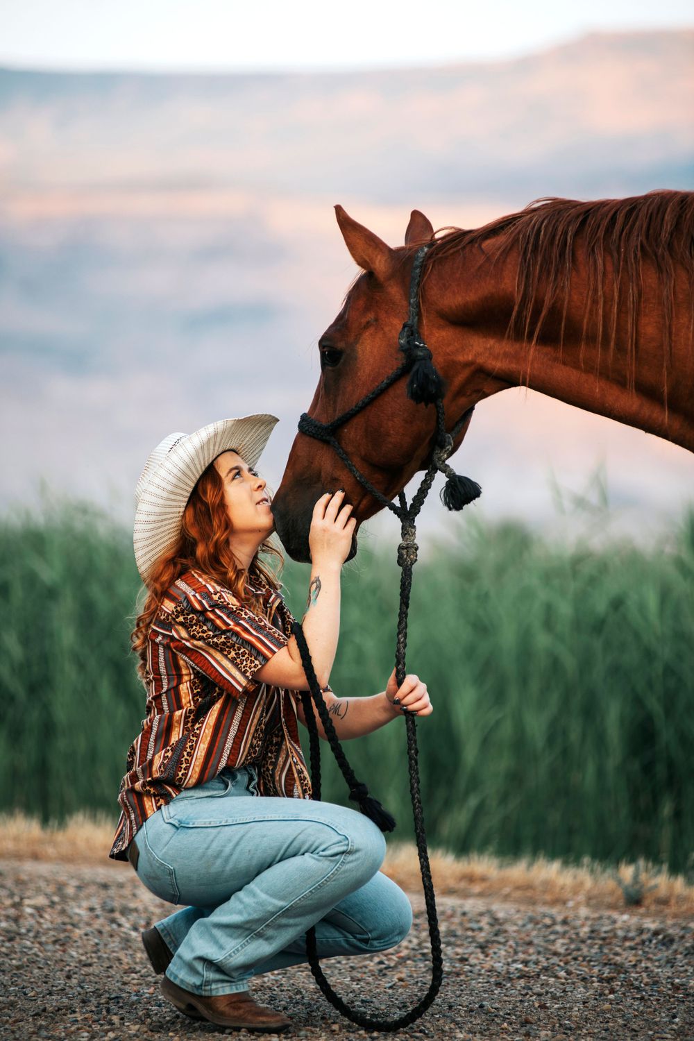 Sweet bonding moment between horse and rider against mountain backdrop at dusk.