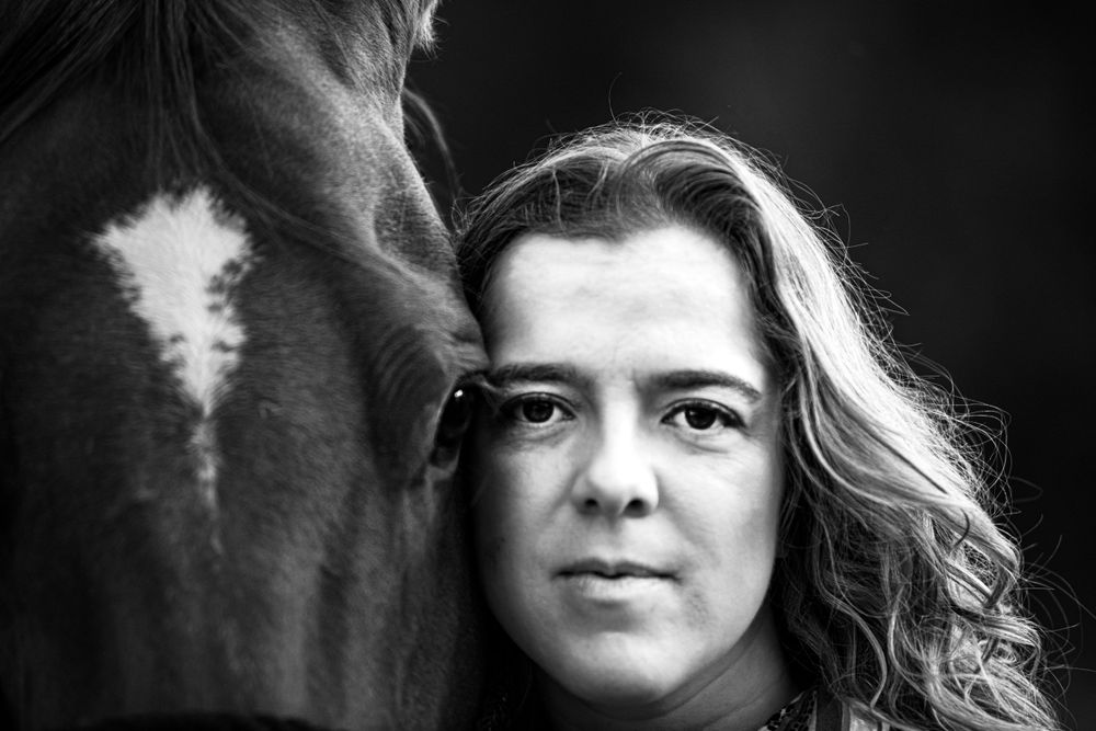Dramatic black and white portrait with horse in soft lighting.