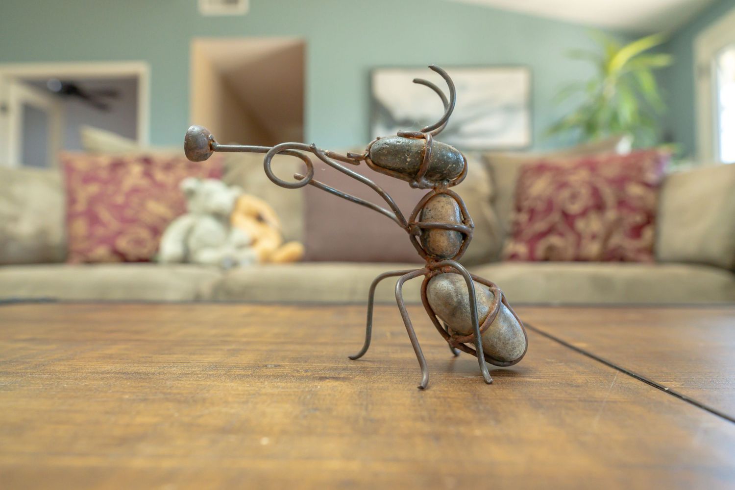 An ant playing trumpet is created out of thin twists of metal & rocks. Image demonstrates f/5.0 aperture creates slightly blur background.