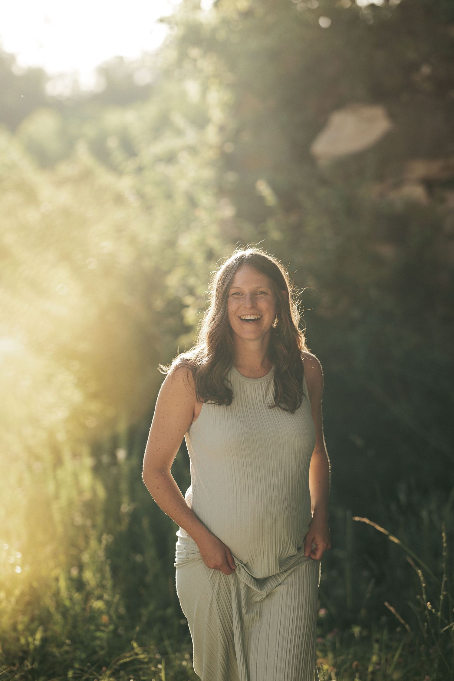 Katie laughing during golden hour maternity photos on the Katy Trail in St. Charles Missouri