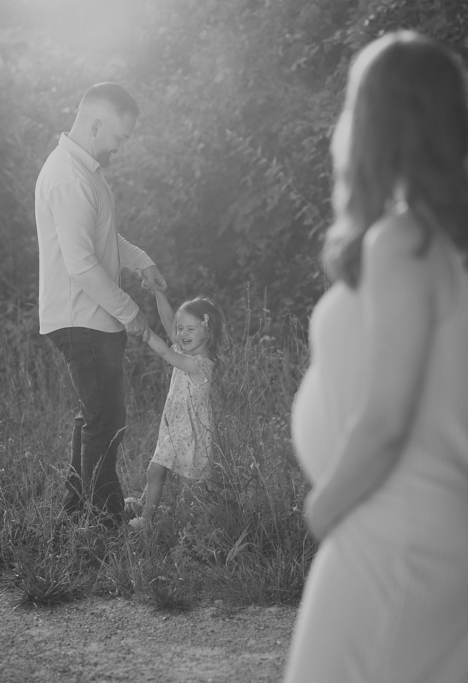 Daddy dancing with daughter during golden hour while mom watches